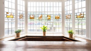A room with large windows, a wooden floor, and two potted plants. - Grosse Gruppenunterkunft im Nationalpark Eifel mit Bar und Terrasse (Schleiden)