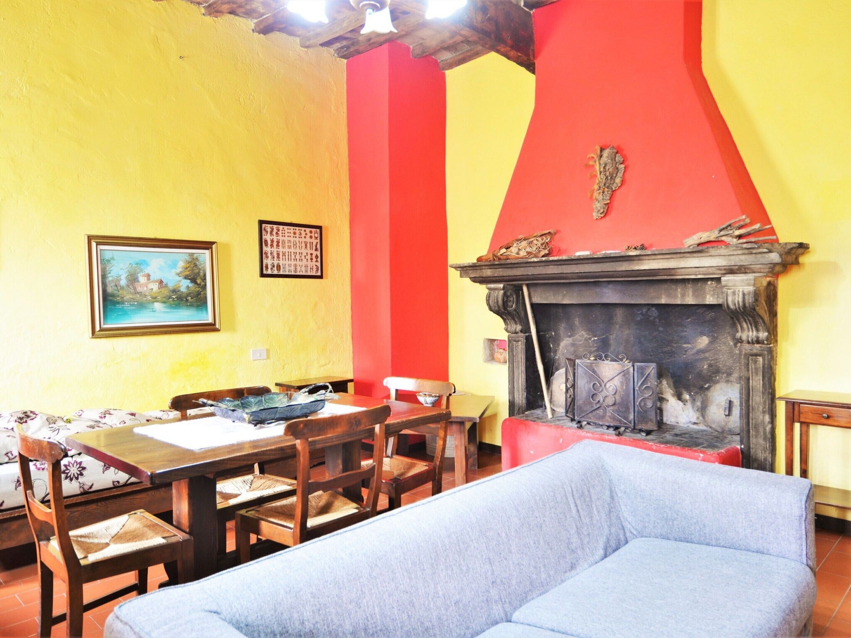 A dining area with a wooden table and chairs, a sofa, and a fireplace.