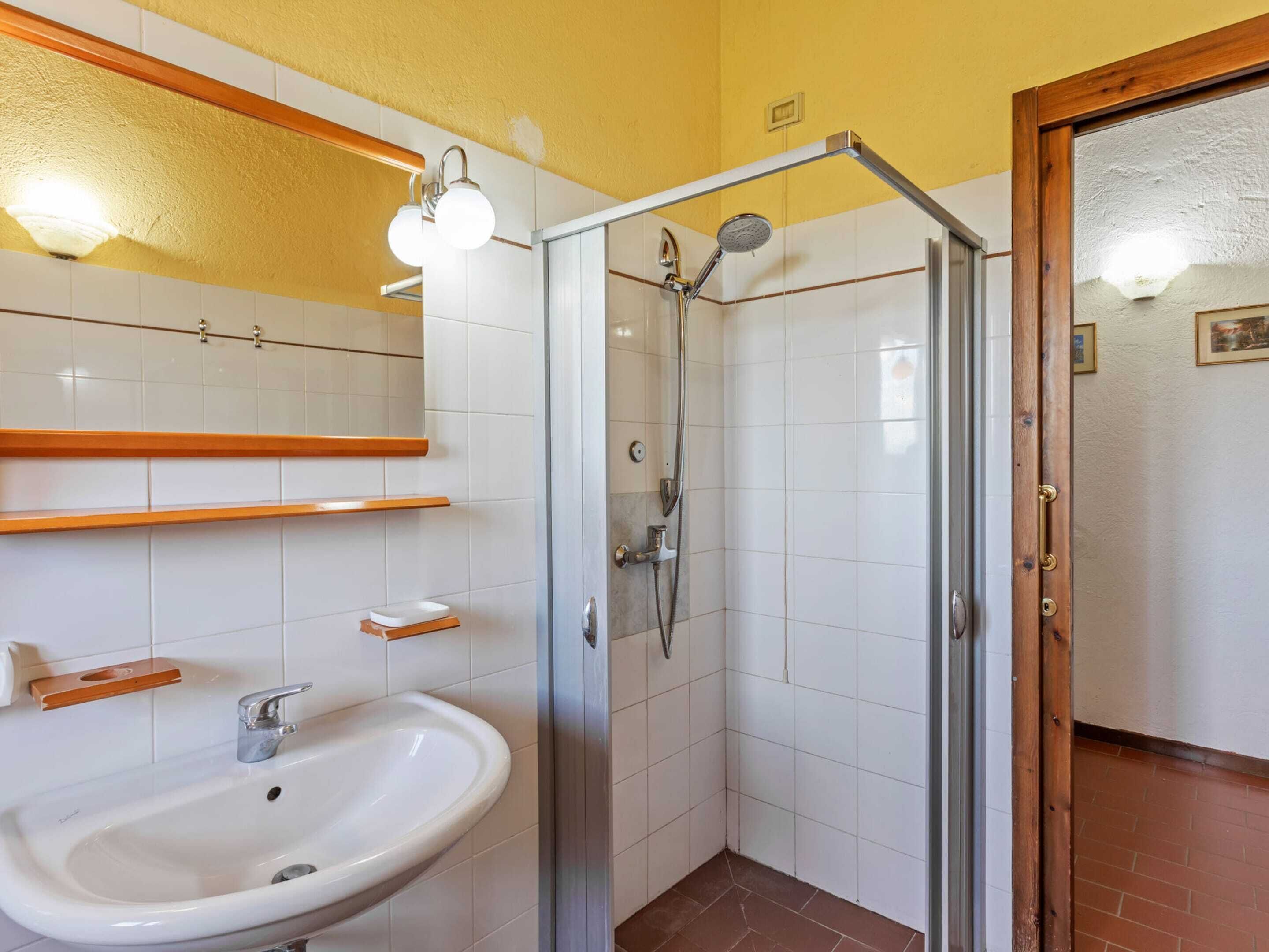 A bathroom with a glass-enclosed shower, a white sink, and a mirror above the sink.