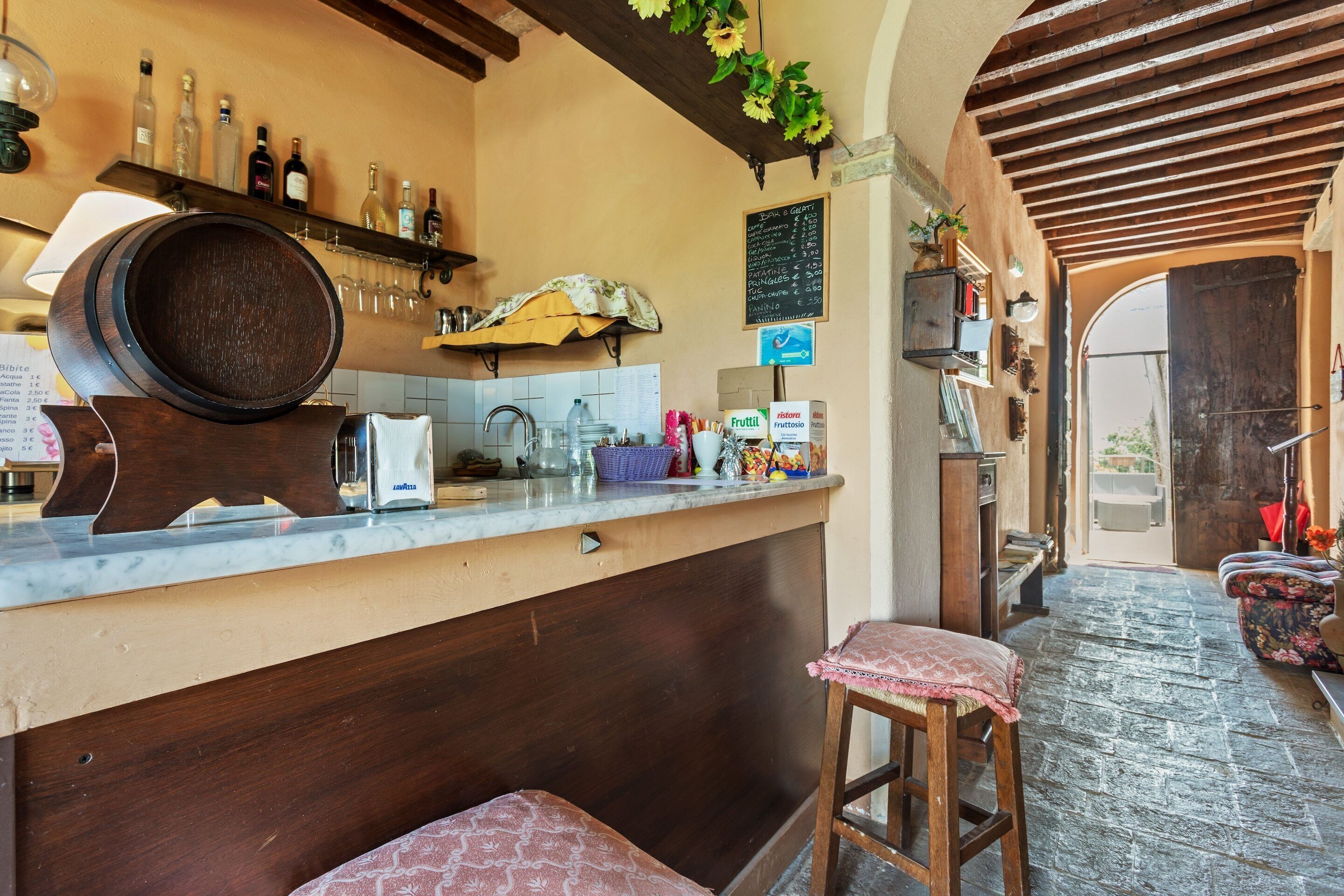 A bar area with a wooden counter, stools, and a chalkboard menu.