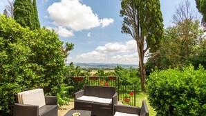 An outdoor patio area with wicker furniture, including a sofa and two armchairs, surrounded by lush greenery and a view of distant hills. - Rustic Holiday Home in Citta di Castello With Swimming Pool (Città di Castello)