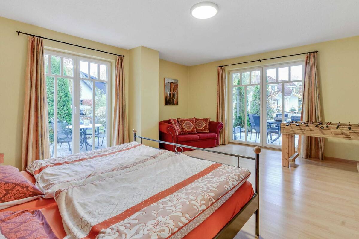 A room with a bed, a red sofa, and a foosball table.
