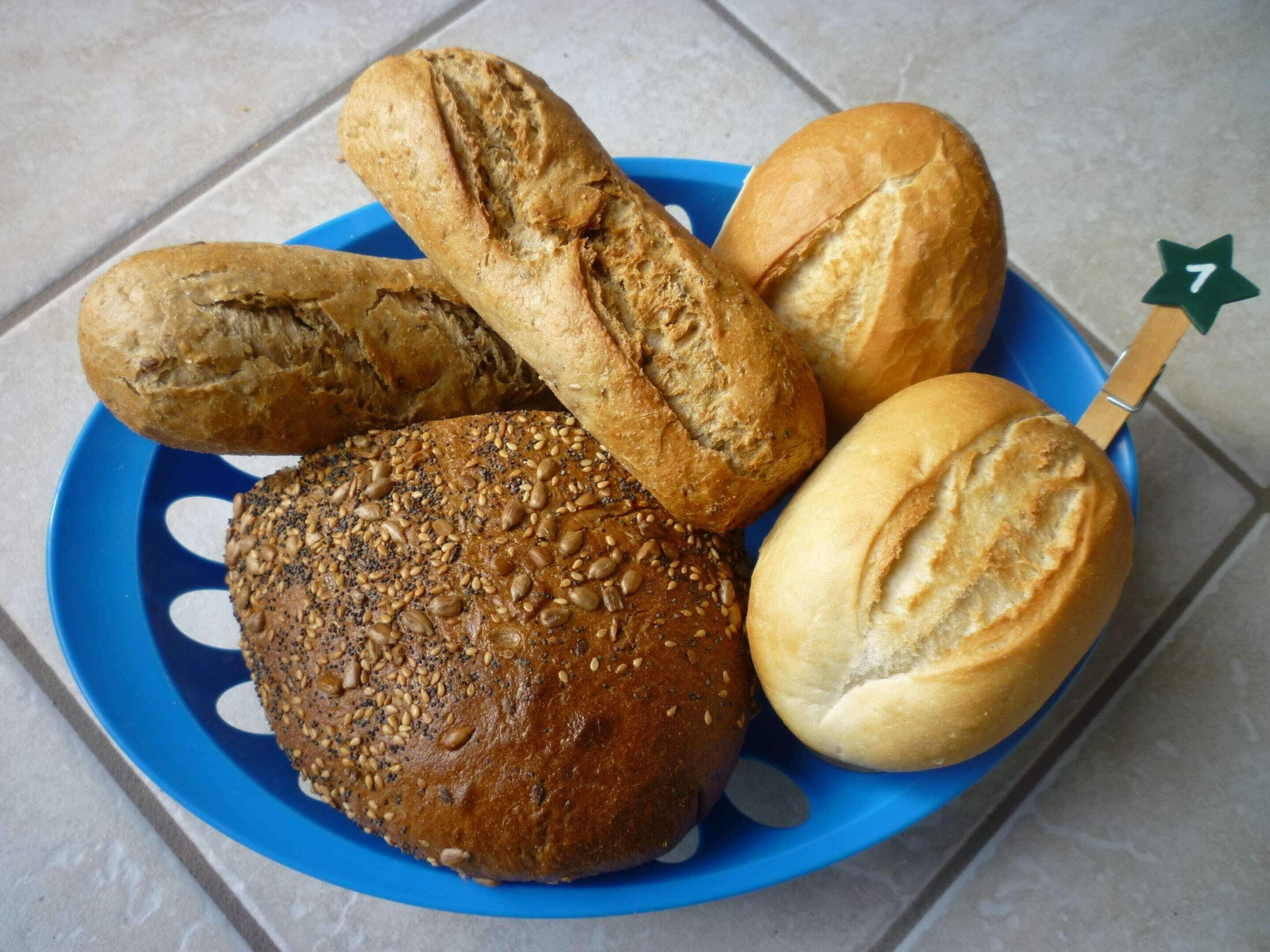 En tallrik med olika sorters bröd, inklusive ett runt bröd med frön och en baguette.