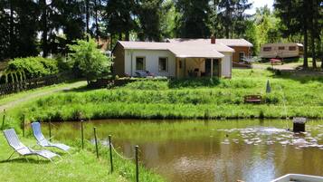A lakeside property with a house, a dock, and a row of lounge chairs.