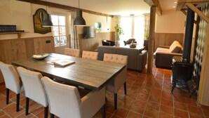 A dining area with a wooden table and chairs, a sofa, and a fireplace. - Pleasant Holiday Home Near the Centre of Haaren (Haaren)