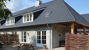 A two-story house with a grey tiled roof, a wooden deck, and a wicker fence. - Pleasant Holiday Home Near the Centre of Haaren (Haaren)