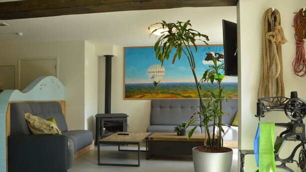 A living room with a sofa, a coffee table, a potted plant, a painting, and a bicycle. - Pleasant Holiday Home Near the Centre of Haaren (Haaren)