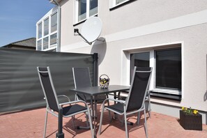 An outdoor patio with a table and chairs, a satellite dish, and a basket with flowers. - Modern Bungalow in Warnkenhagen Near Wellness (Kalkhorst)