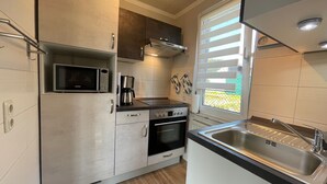 Una cocina compacta con microondas, cafetera, horno y pileta.