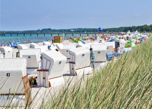 Eine Reihe von nummerierten Mobilheimen direkt am Strand, mit einem Steg im Hintergrund.