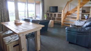 Un salon chaleureux avec une table à manger en bois, un canapé bleu et un escalier.
