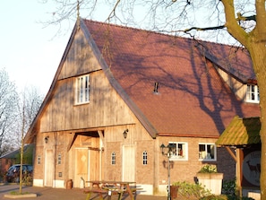 Ein Holzhaus mit geneigtem Dach, einer Holztür und einer Bank davor.