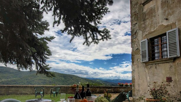 An outdoor dining area with a table set for two, overlooking a mountainous landscape. - Apartment in a Farmhouse With Swimming Pool (Rufina)