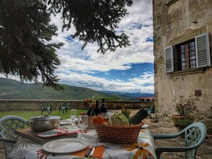 Un espace de restauration en plein air avec une table dressée pour deux personnes, offrant une vue sur un paysage montagneux.