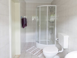A modern bathroom with a glass-enclosed shower, a toilet, and a towel rack with towels.