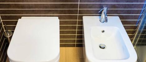 A bathroom with a bidet, a sink, and a toilet.