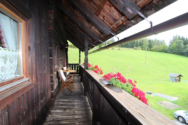 A wooden balcony with a view of a green field.