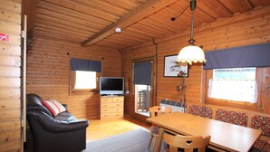A wooden cabin interior with a sofa, TV, dining table, and chairs. - Characterful old Farmhouse With 4 Apartments in Fresach / Carinthia With Garden (Fresach)