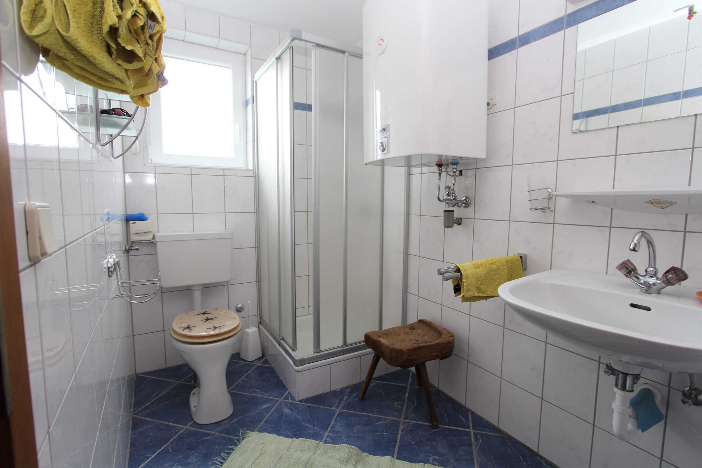Une salle de bain équipée de toilettes, d’une douche, d’un lavabo et d’un petit tabouret.