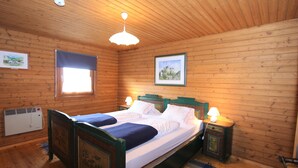 A wooden-paneled room with a bed, two bedside lamps, a window with a blind, and a framed picture on the wall. - Characterful old Farmhouse With 4 Apartments in Fresach / Carinthia With Garden (Fresach)