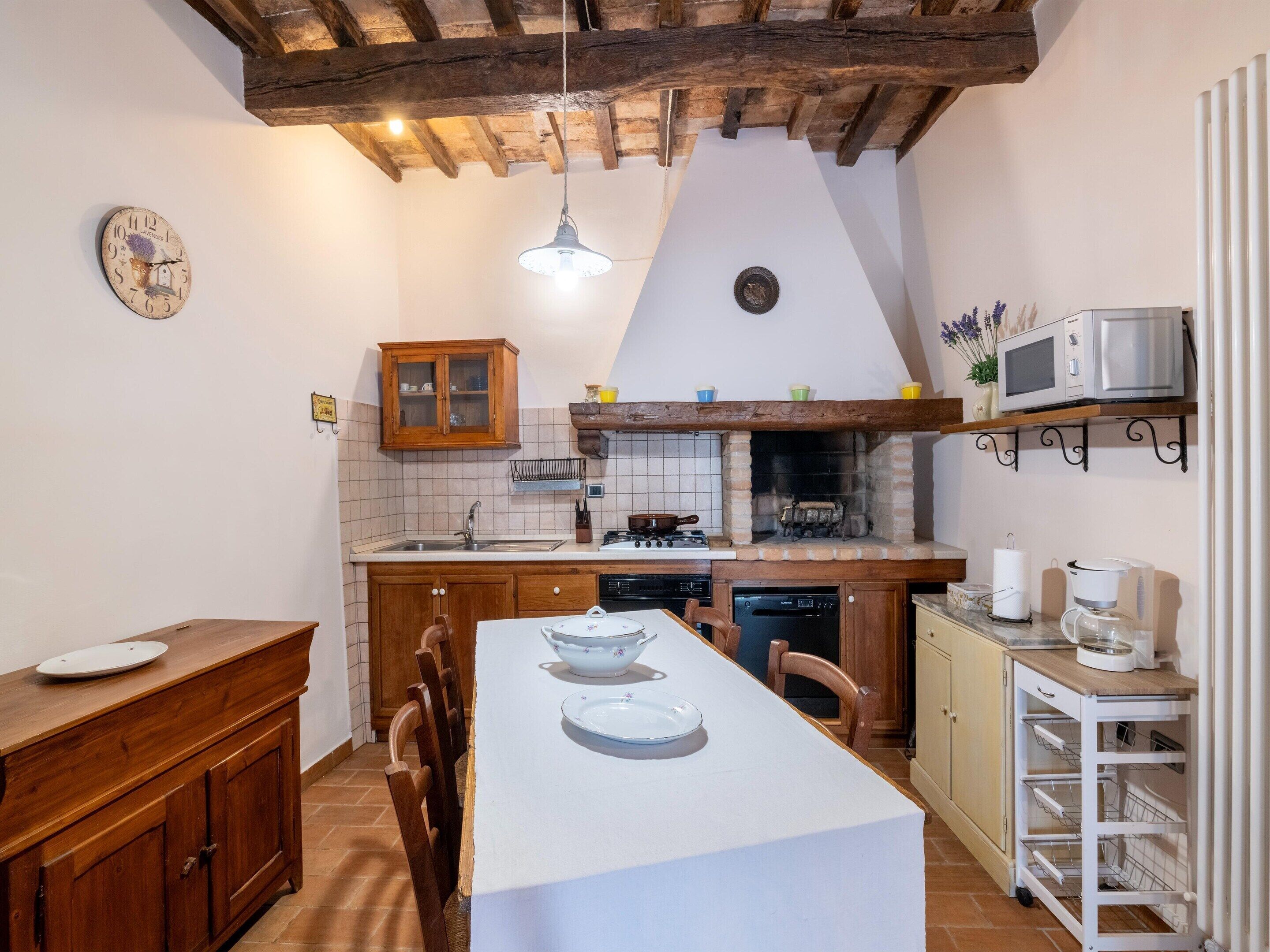 Een keuken met een houten tafel, kastjes, een fornuis en een magnetron.
