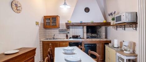 Een keuken met een houten tafel, kastjes, een fornuis en een magnetron.