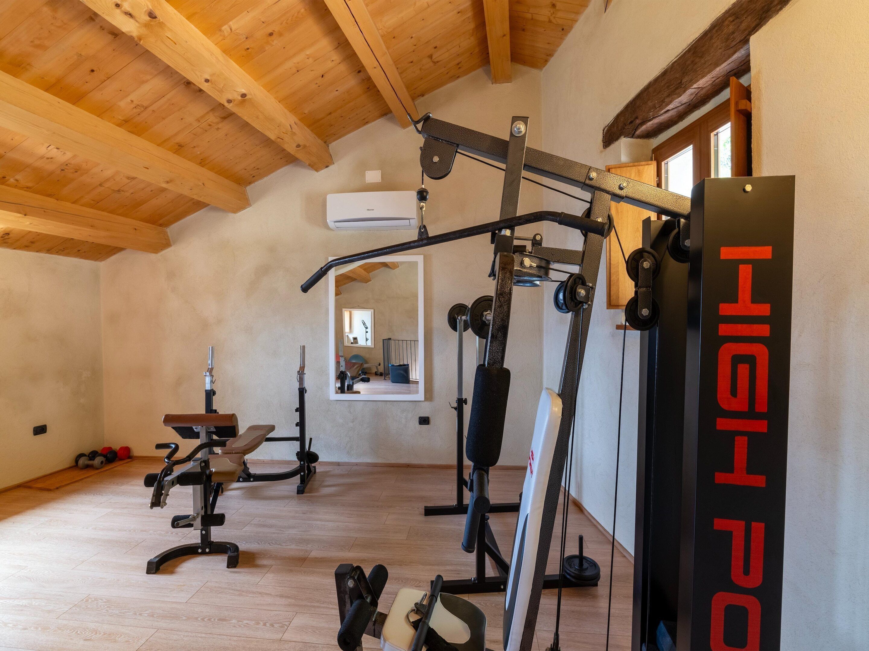 A gym with wooden beams, exercise equipment, and a mirror.