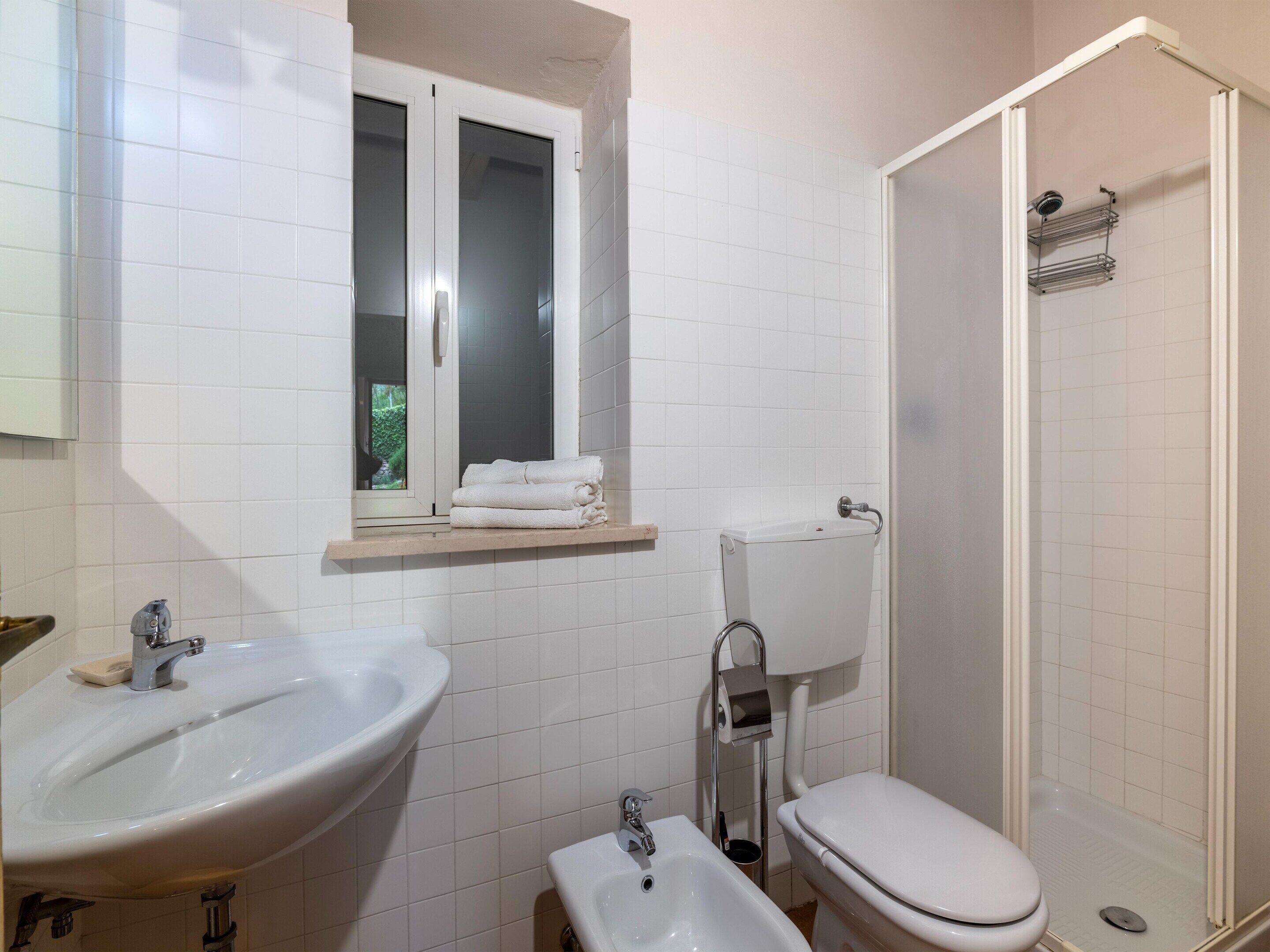 A bathroom with a sink, bidet, toilet, and a shower.