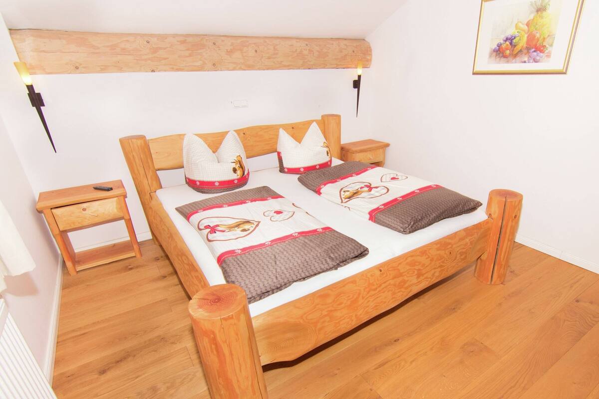 Un lit en bois avec une tête de lit, une table de chevet et une petite table à poser près du lit.