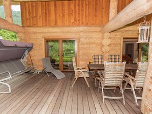 A wooden cabin with a deck, a grill, and a table with chairs. - Pleasant Apartment in Ruhpolding With Swimming Pool (Ruhpolding)