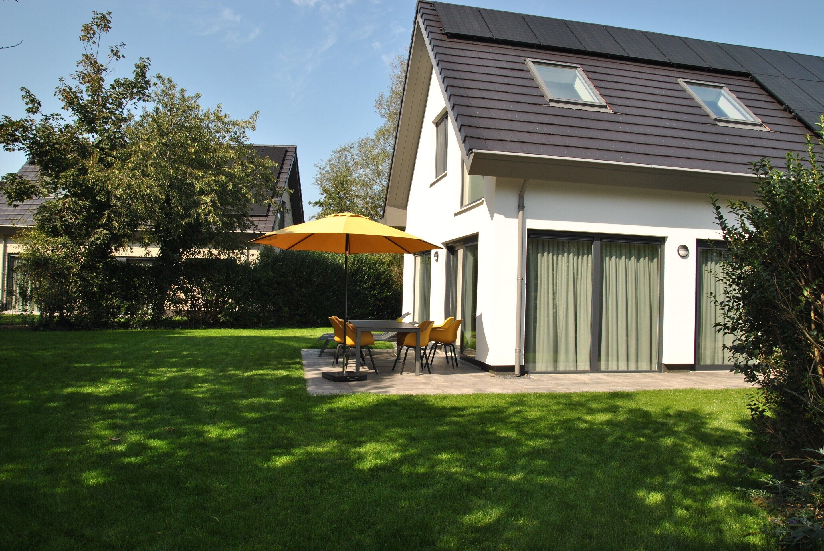 A modern house with a covered patio, a lawn, and a garage.