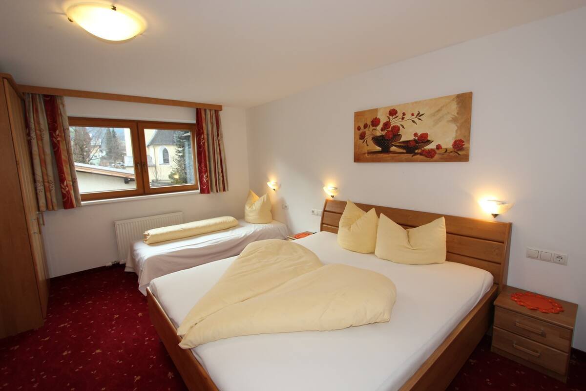 A hotel room with two beds, a large painting, and a window with curtains.