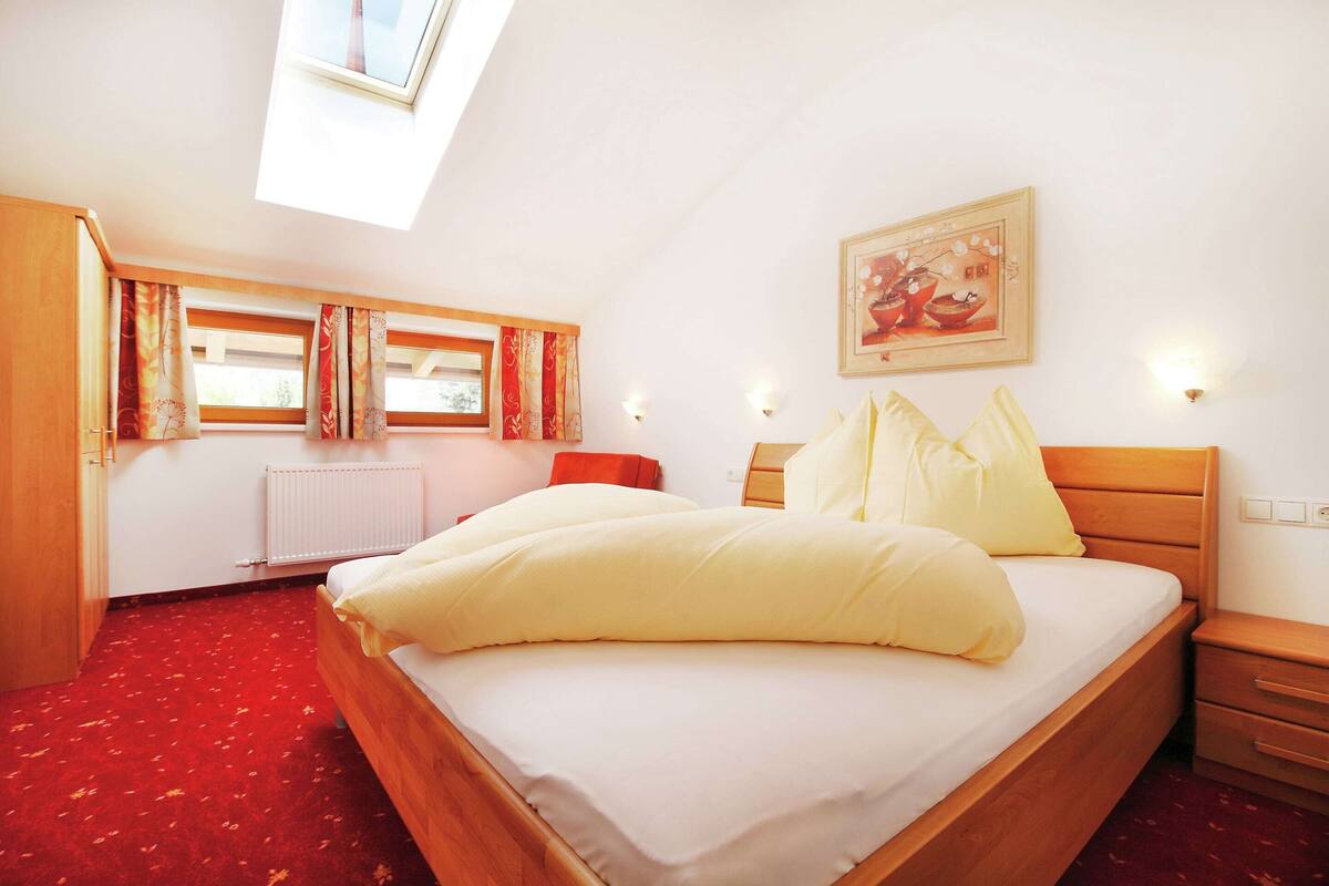 A bedroom with a wooden bed, a skylight, a radiator, and a painting on the wall.