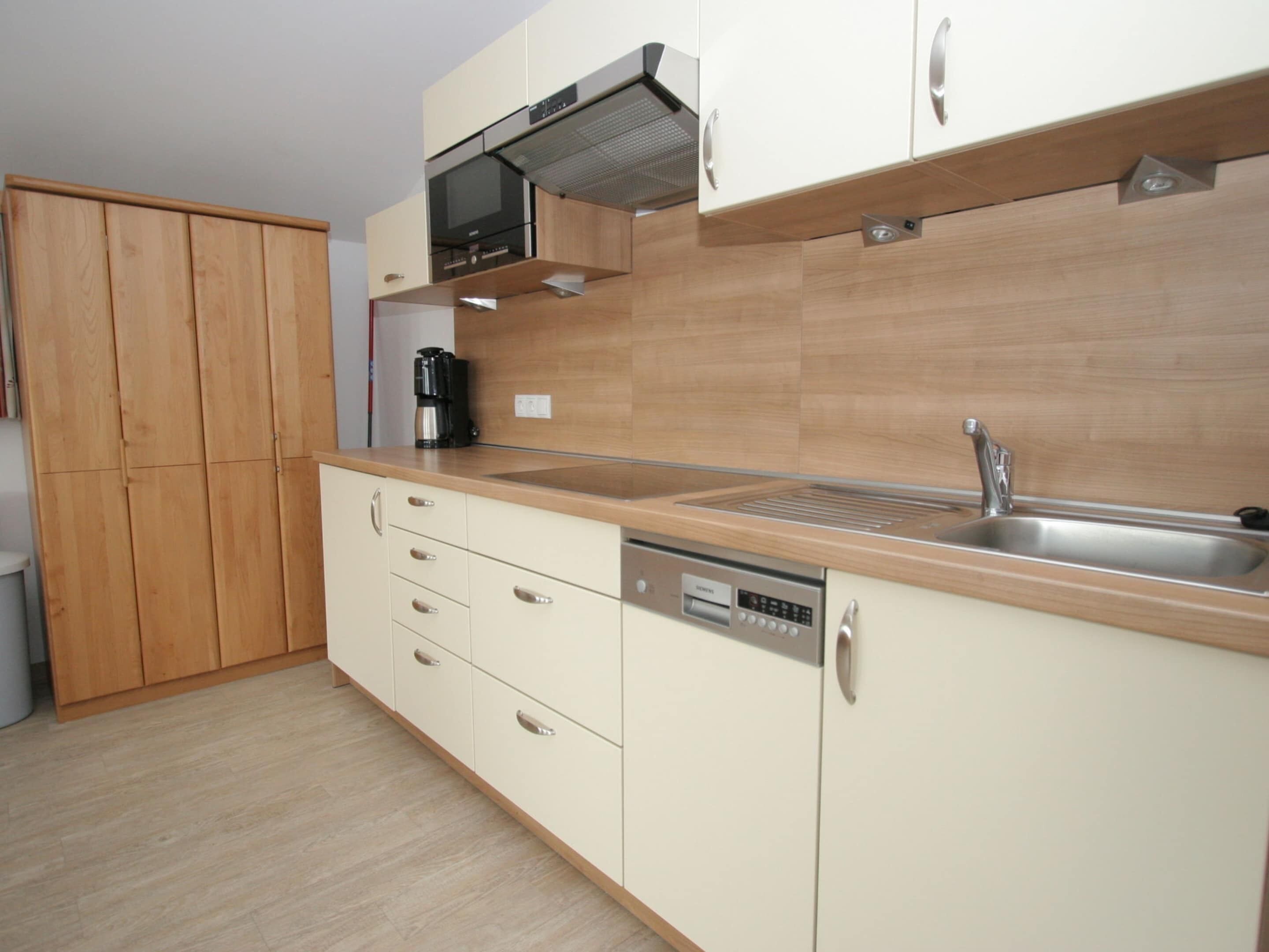 A modern kitchen with wooden cabinets, a stainless steel sink, and a built-in oven.
