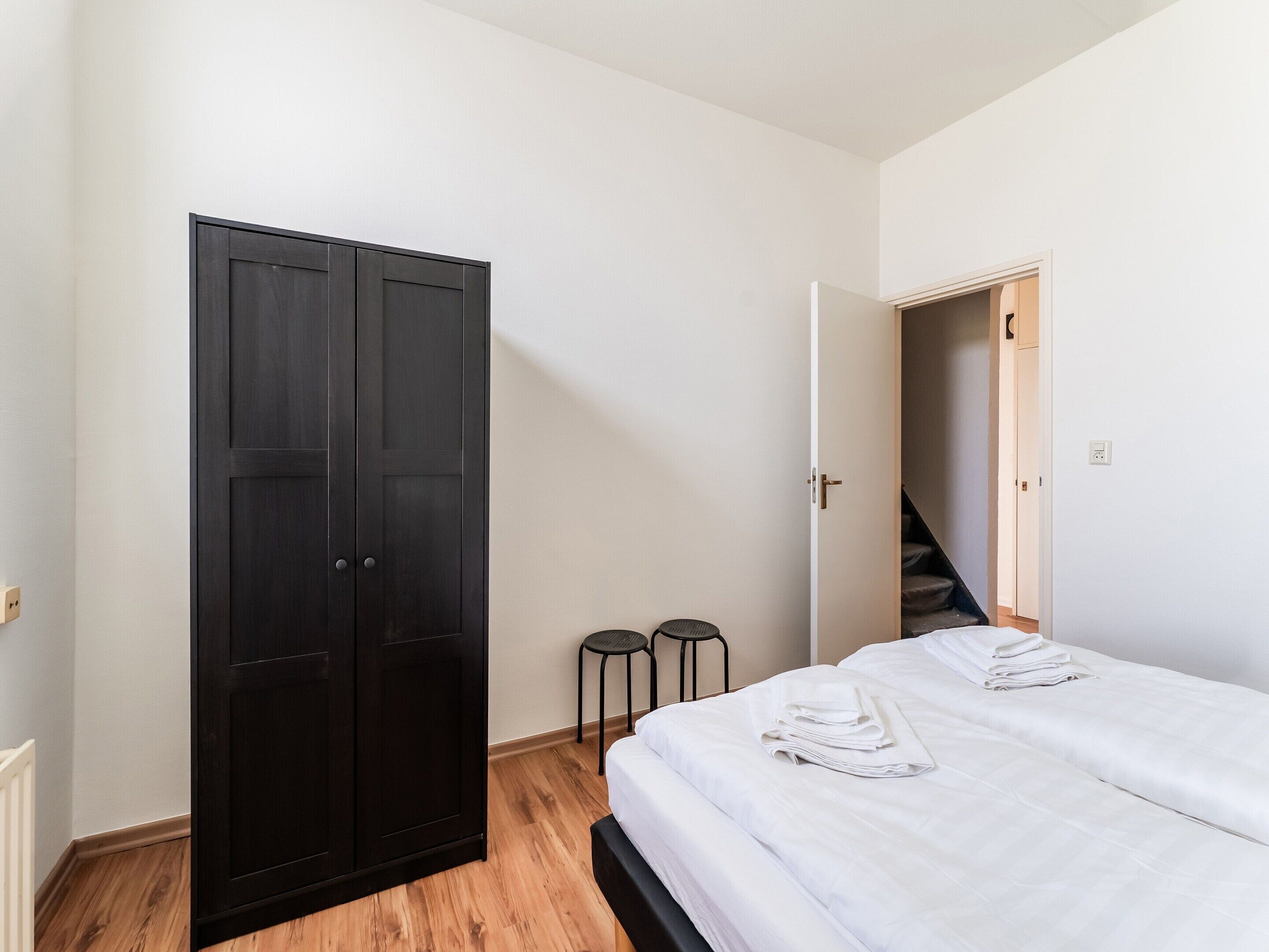 A bedroom with a bed, a wardrobe, and a staircase.