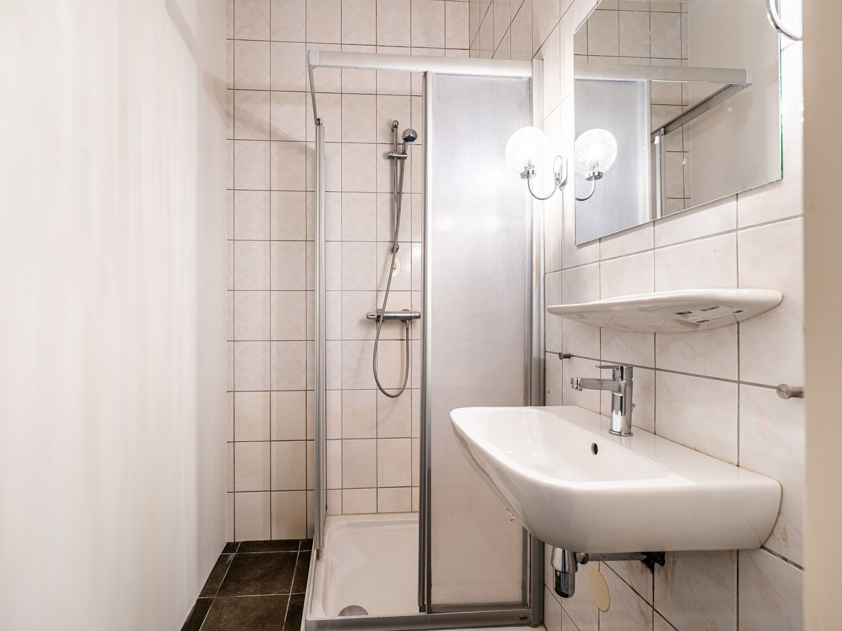 Un bagno moderno con doccia, lavandino e specchio.