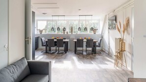 A modern dining area with a large table and chairs, a sofa, and a vase with pampas grass. - Spacious Farmhouse in Silvolde With Garden (Silvolde)