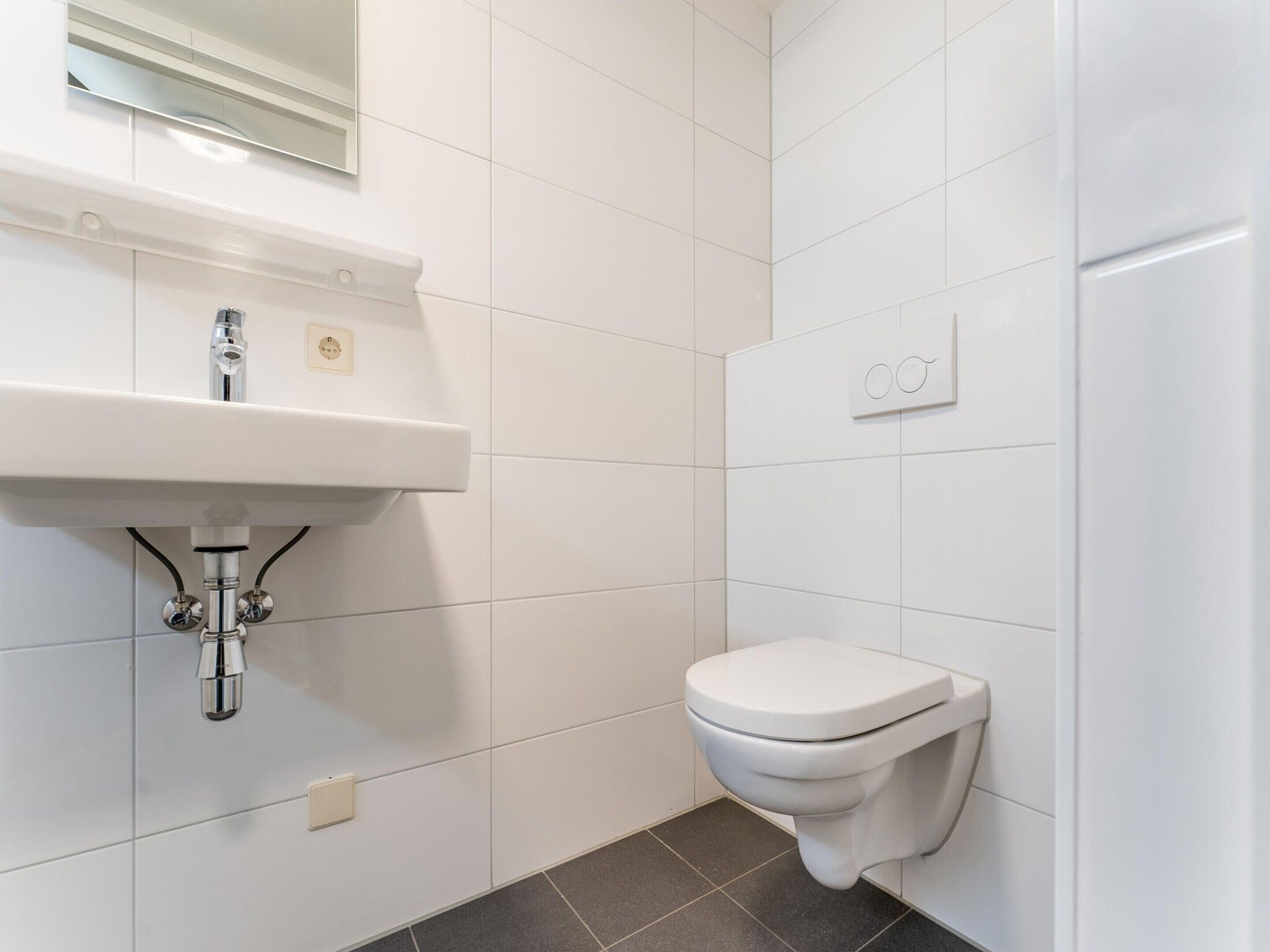 A bathroom with a white sink, a toilet, and a mirror above the sink.