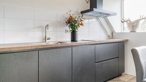 A modern kitchen with a built-in sink, a black range hood, and a window with a view of trees. - Spacious Farmhouse in Silvolde With Garden (Silvolde)
