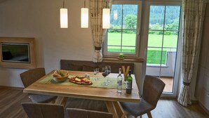 A dining area with a wooden table, four chairs, a television, and a window with a view of greenery. - Cozy Apartment Near Ski Area in Mayrhofen (Schwendau)