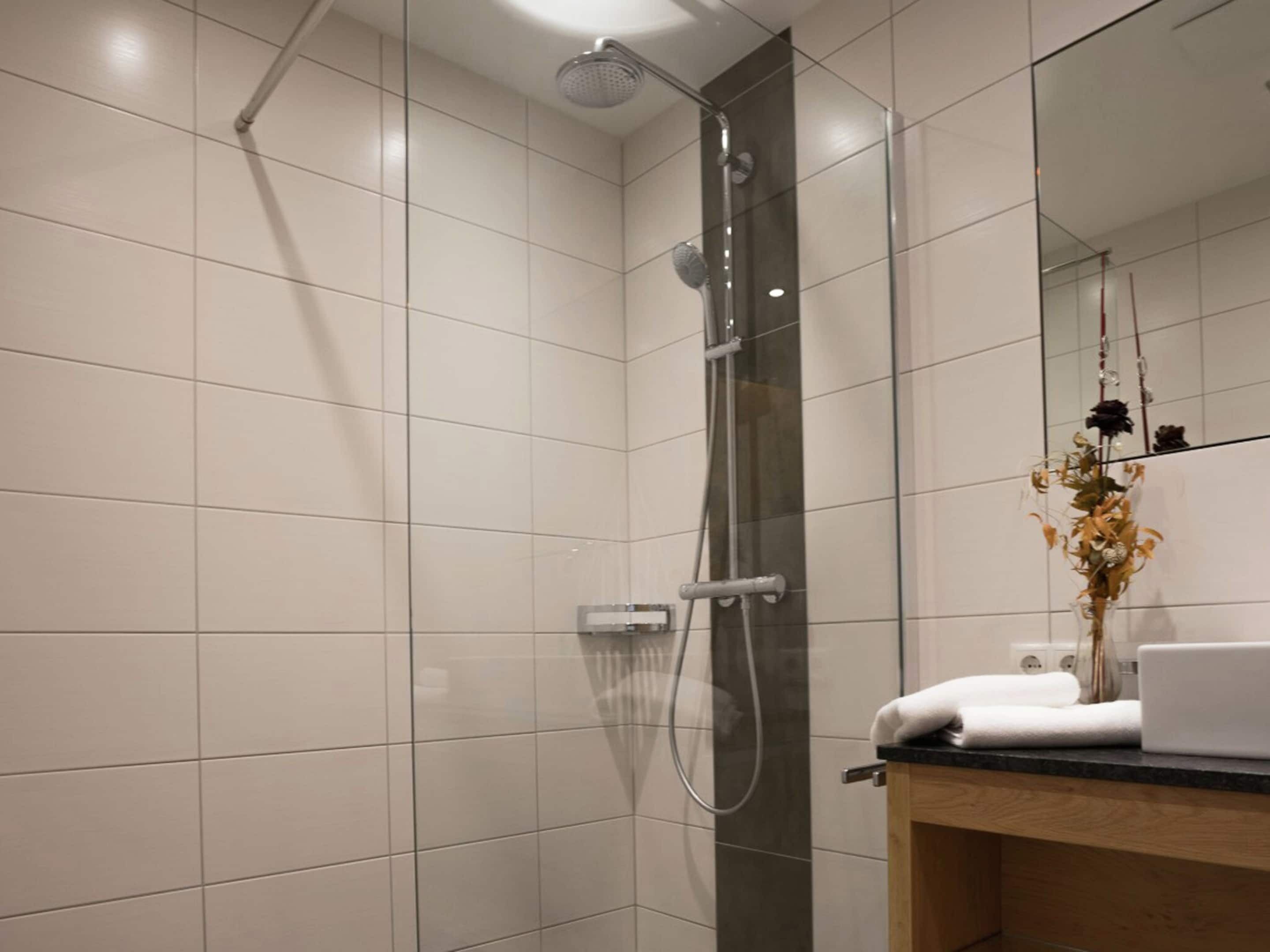 Un baño moderno con cabina de ducha de vidrio, tocador de madera y espejo.