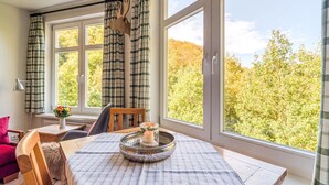 A cozy room with a large window, a wooden table with a candle, and plaid curtains. - Rustic Apartment With Garden in Bad Harzburg Germany (Bad Harzburg)
