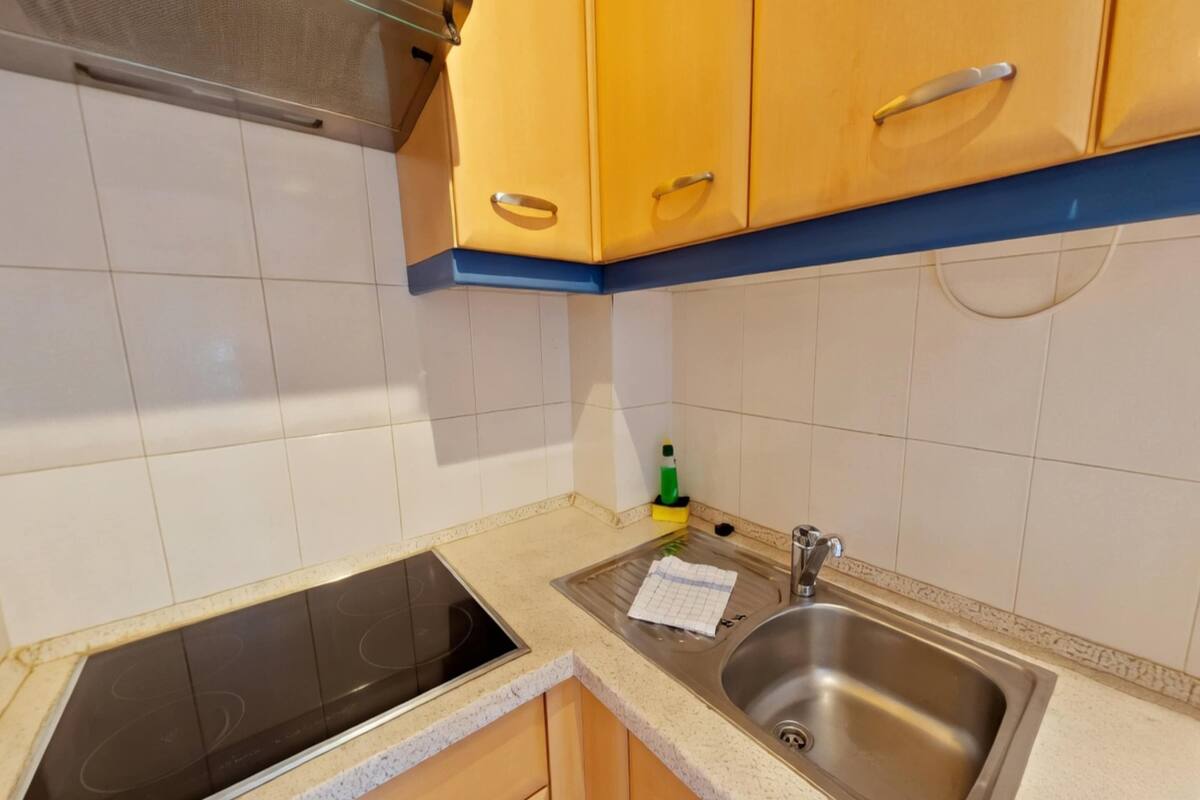 Una cocina con estufa, lavaplatos y armarios.