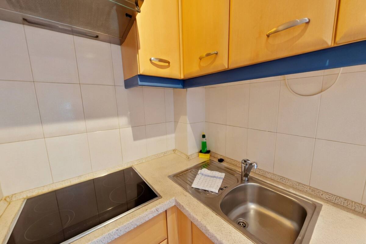 Una cocina con estufa, pileta y muebles de madera.