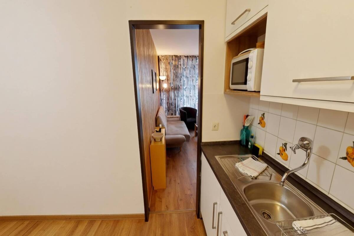 Una cocina con microondas, lavamanos y salpicadero de azulejos.