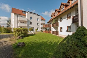 A residential building with a paved driveway, a well-maintained lawn, and a small patio area. - Spacious Apartment Near Forest in Bad Durrheim (Bad Duerrheim)