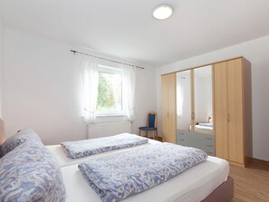 A bedroom with a bed, a chair, a wardrobe, and a window. - Spacious Apartment Near Forest in Bad Durrheim (Bad Duerrheim)