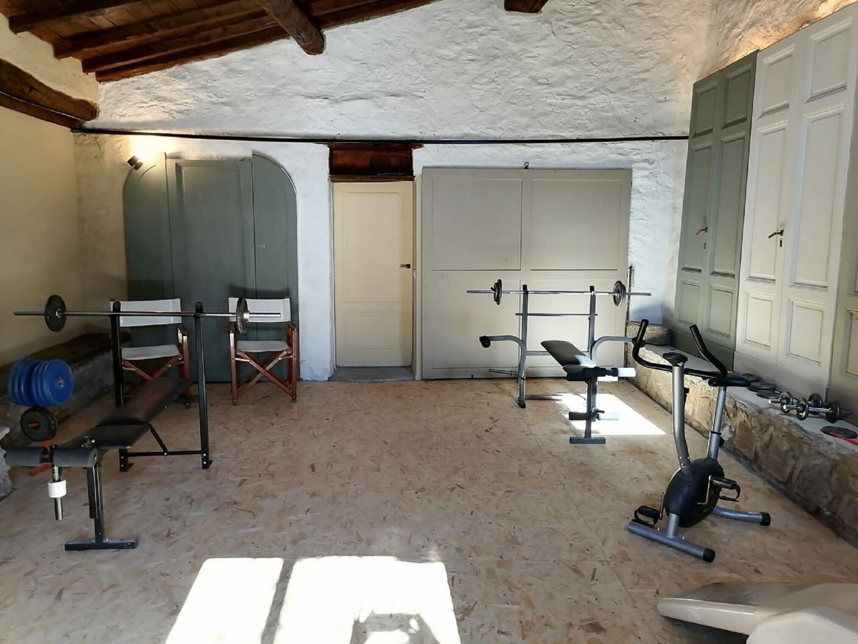 A gym with a bench press, squat rack, and exercise bike.