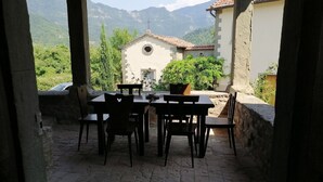 An outdoor patio with a stone table and chairs, a potted plant, and a view of mountains. - Comfy Home in San Godenzo With Lake Nearby (San Godenzo)