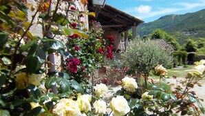 A garden with roses and a stone building with a wooden roof. - Comfy Home in San Godenzo With Lake Nearby (San Godenzo)